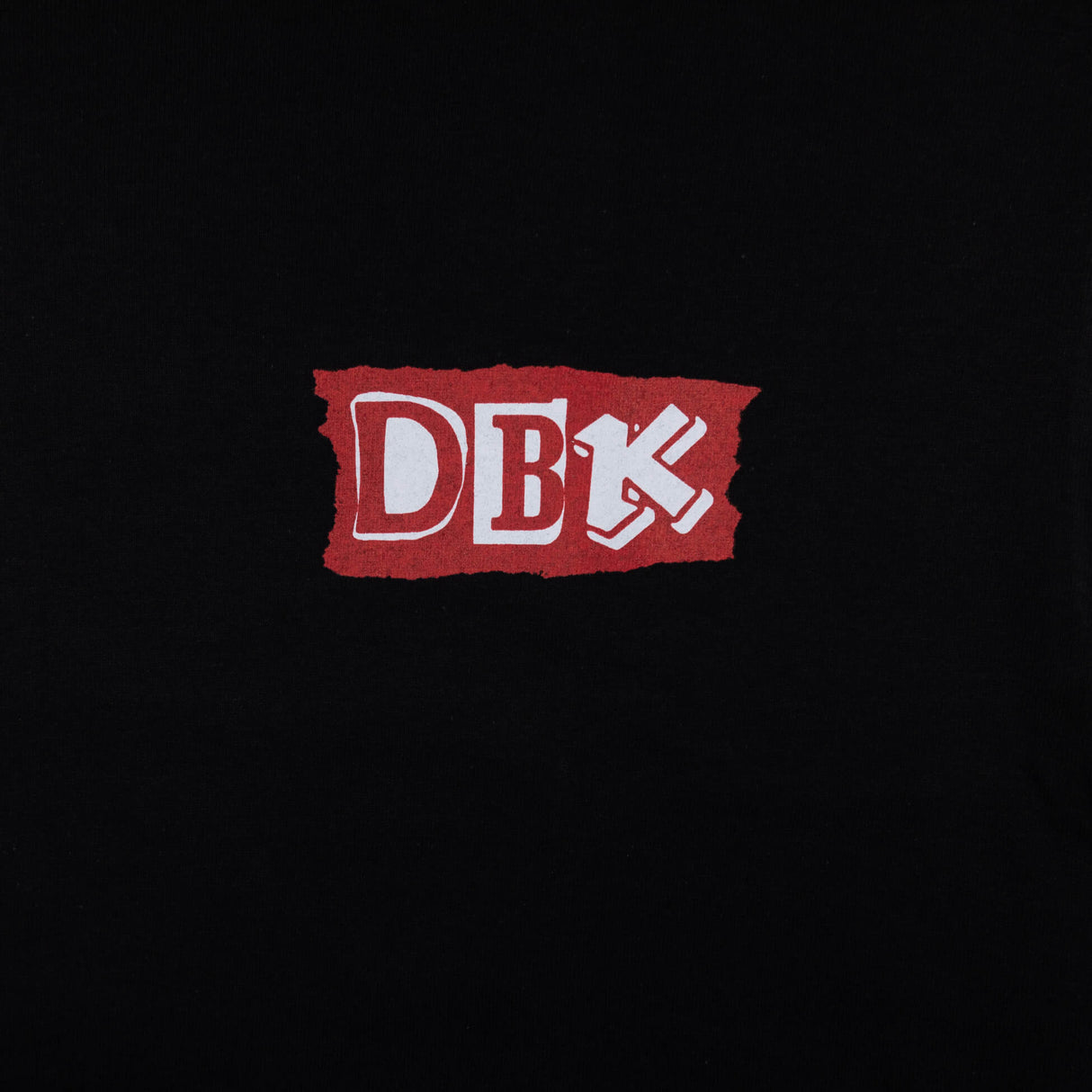 Black Shifting Gears tee close-up of red DBK logo