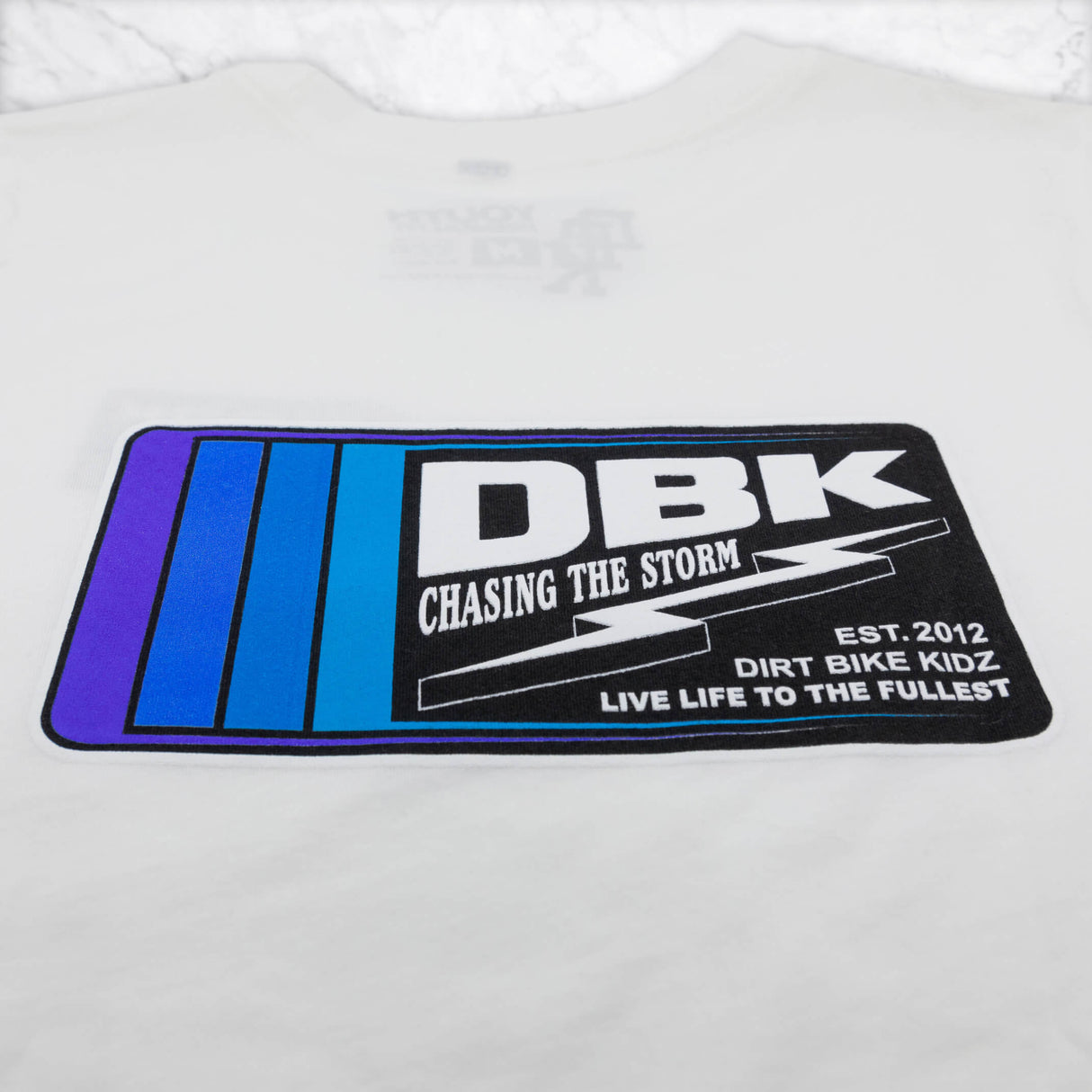 Youth premium tee logo graphic close-up, white with DBK rectangular patch