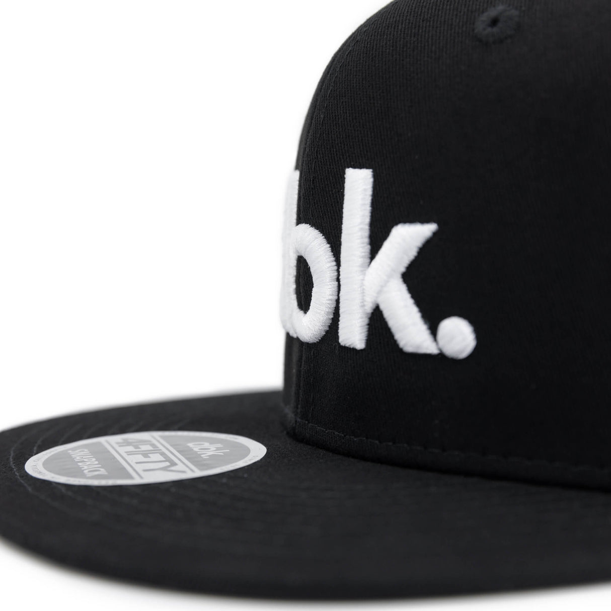 Black snapback cap side view with partial white dbk logo and front sticker label.