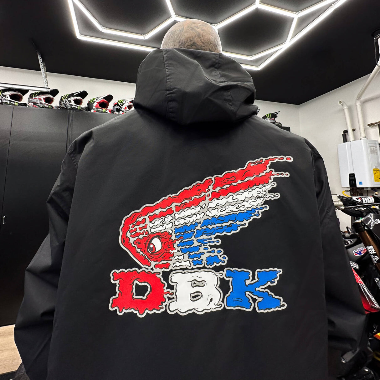 Black windbreaker jacket with hood and large colorful graphic on back