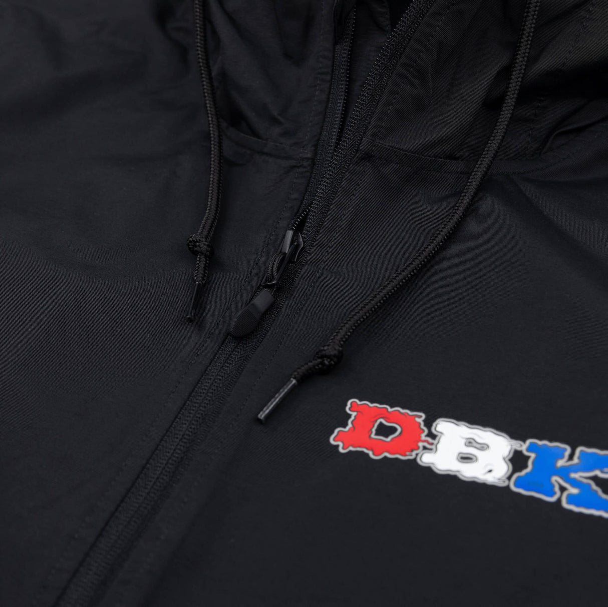 Black windbreaker with front zipper, drawstrings, and small colorful chest graphic