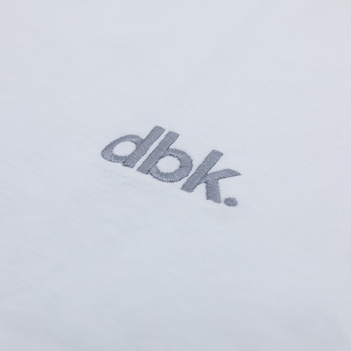 White crew T-shirt with gray dbk logo close-up