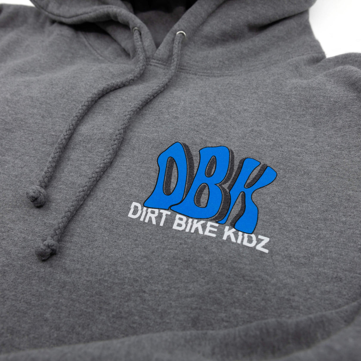 Gray hoodie logo close-up: blue DBK with DIRT BIKE KIDZ text under hood drawstrings