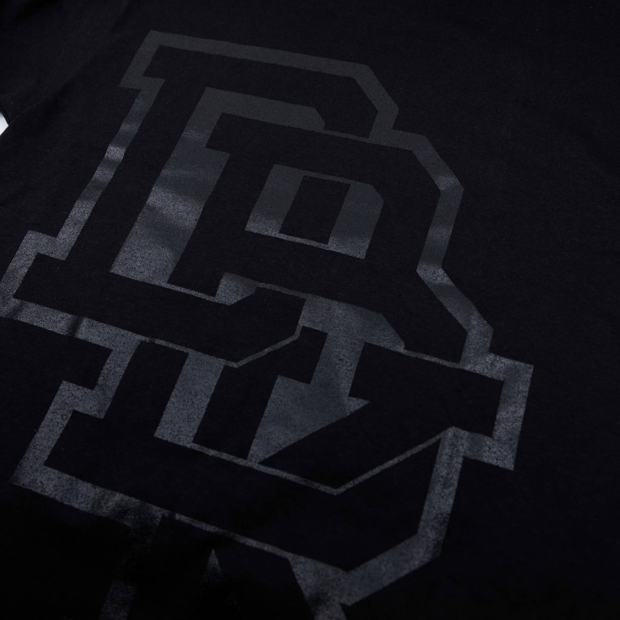 Youth premium tee, close-up of black front logo with dark gray block letters