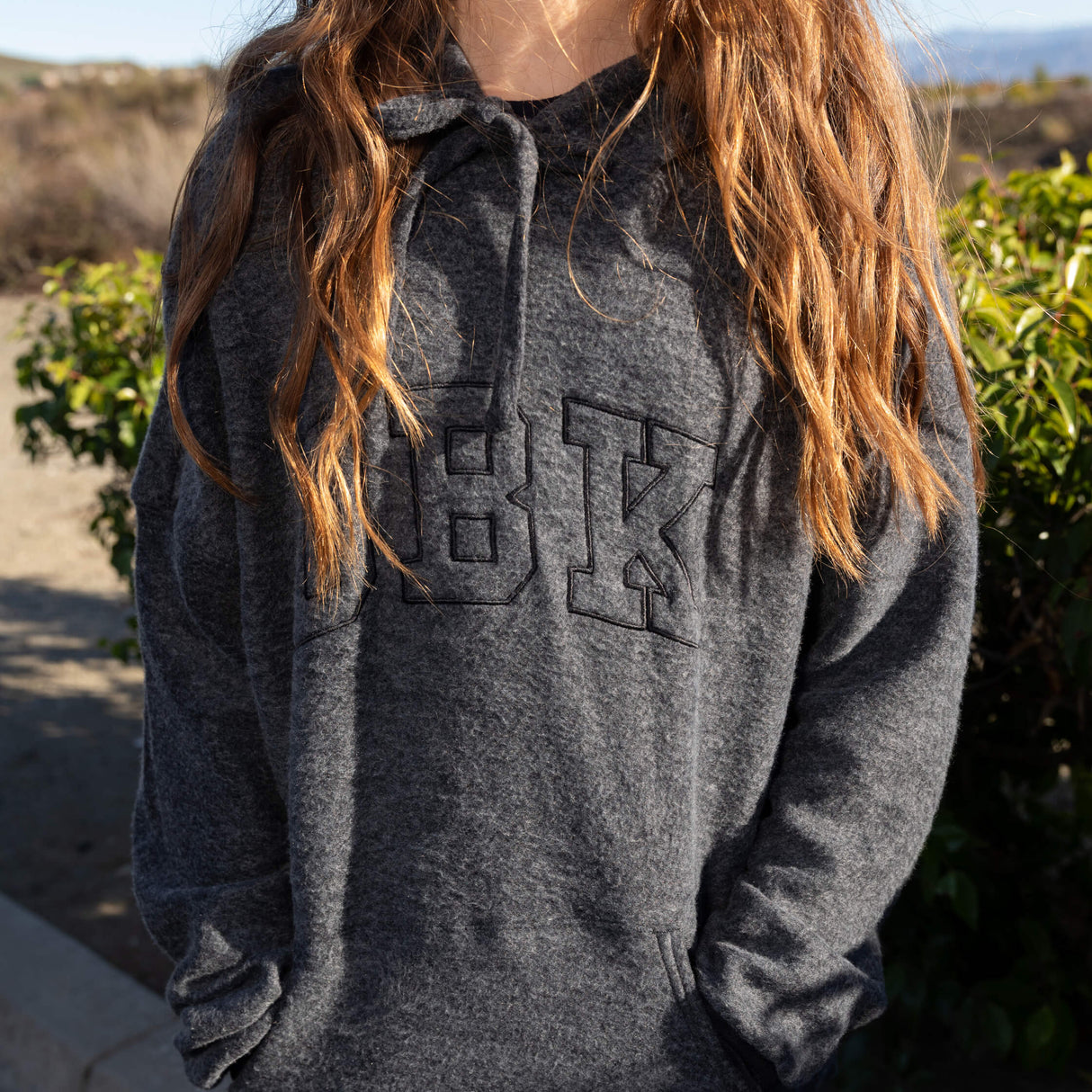 Women’s dark charcoal pullover hoodie with front logo graphic and drawstring hood