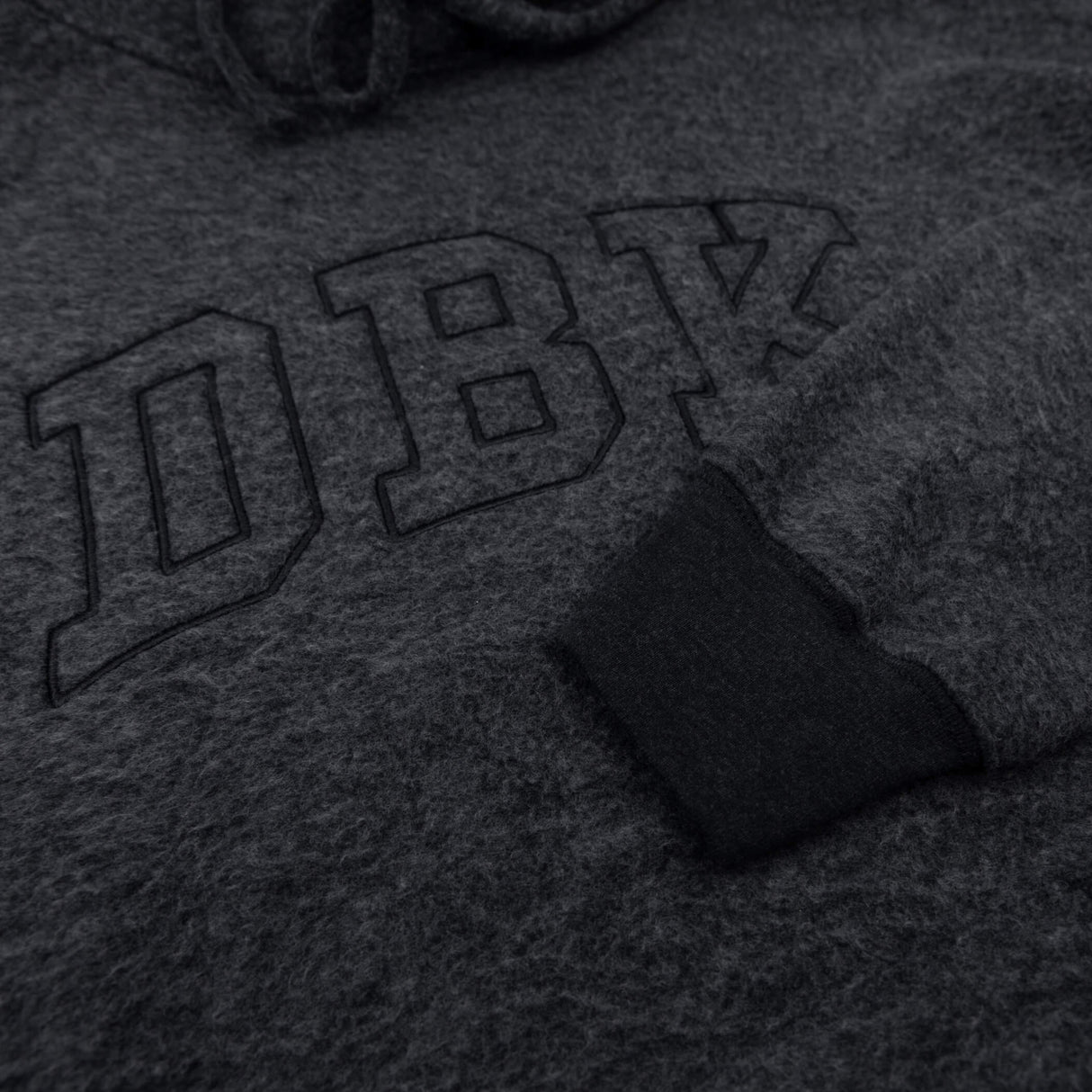 Women’s dark charcoal pullover hoodie close-up of front logo embroidery and fabric texture