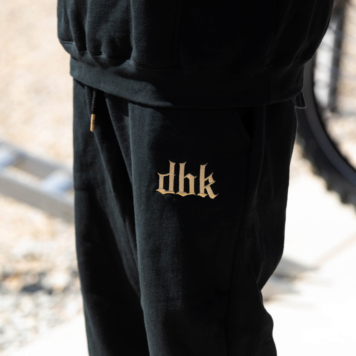 Black premium sweatpants with small gold logo print on the leg