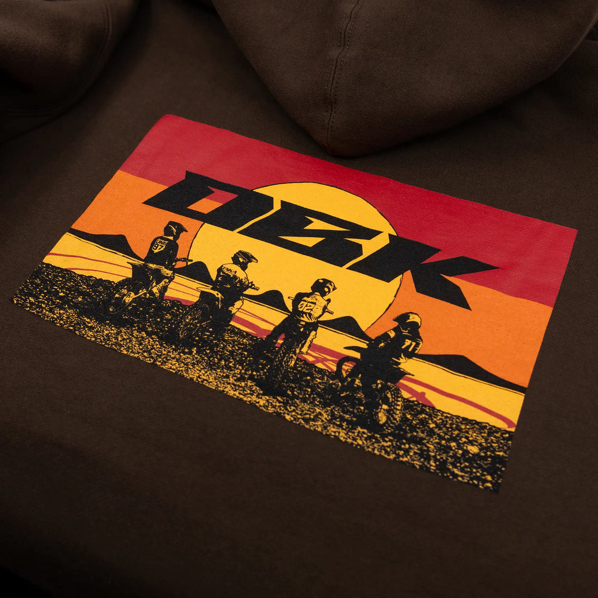 Brown youth hoodie close-up of DKB back graphic with silhouettes and yellow sun