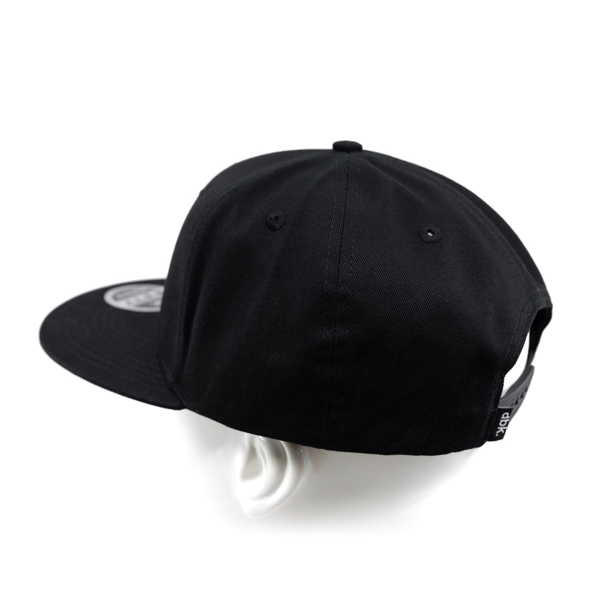 Black snapback cap from side angle with curved brim and crown seams.