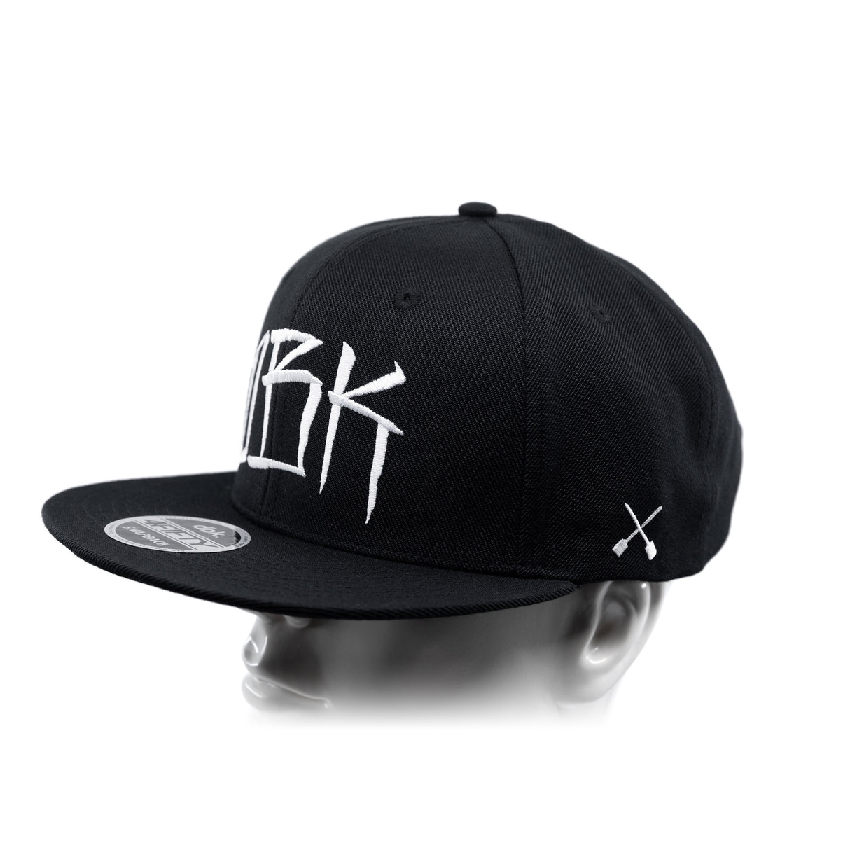 Black baseball cap with partial white 'DBK' lettering and white crossbones on the side