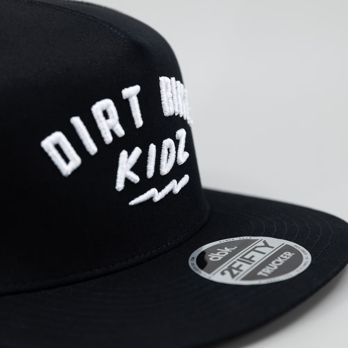 Black cap with white 'DIRT BIKE KIDZ' logo and 'dbk 2FIFTY TRUCKER' patch