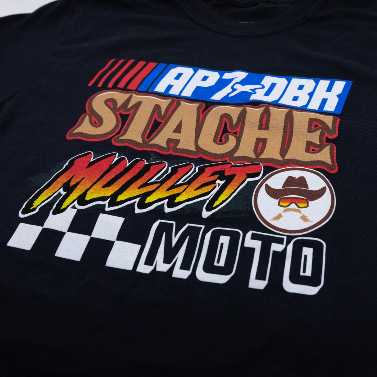 Black womens graphic T-shirt close-up of AP7 DBK Stache and Mullet Moto