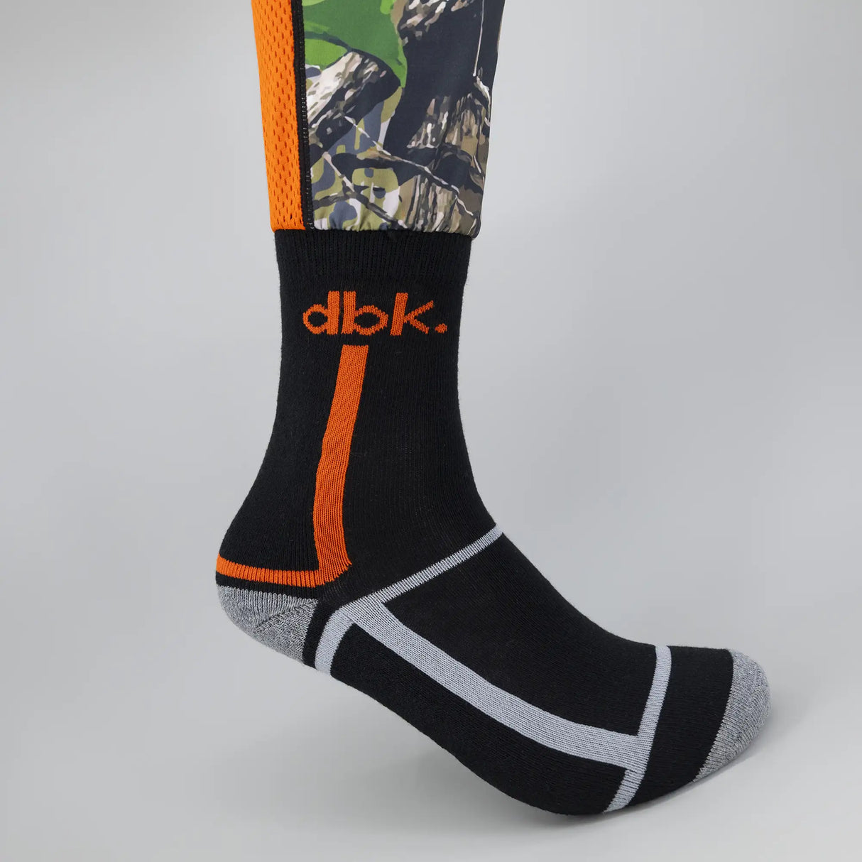 Black crew sock with orange stripe and white band design; camo upper section.