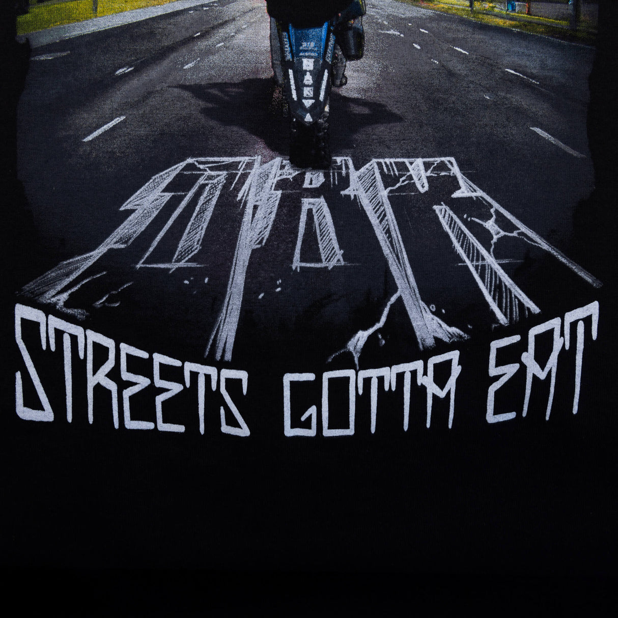 Black T-shirt close-up of back road artwork with large white text graphic