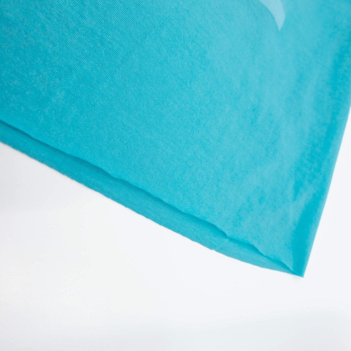 Teal T-shirt hem with soft fabric edge, no visible logos, short-sleeve graphic section.