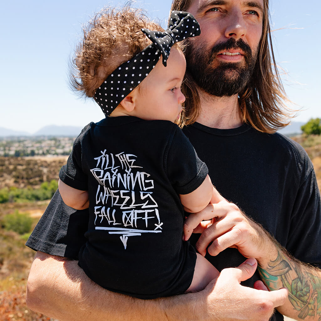 Black baby bodysuit worn by toddler, white graphic text on the back