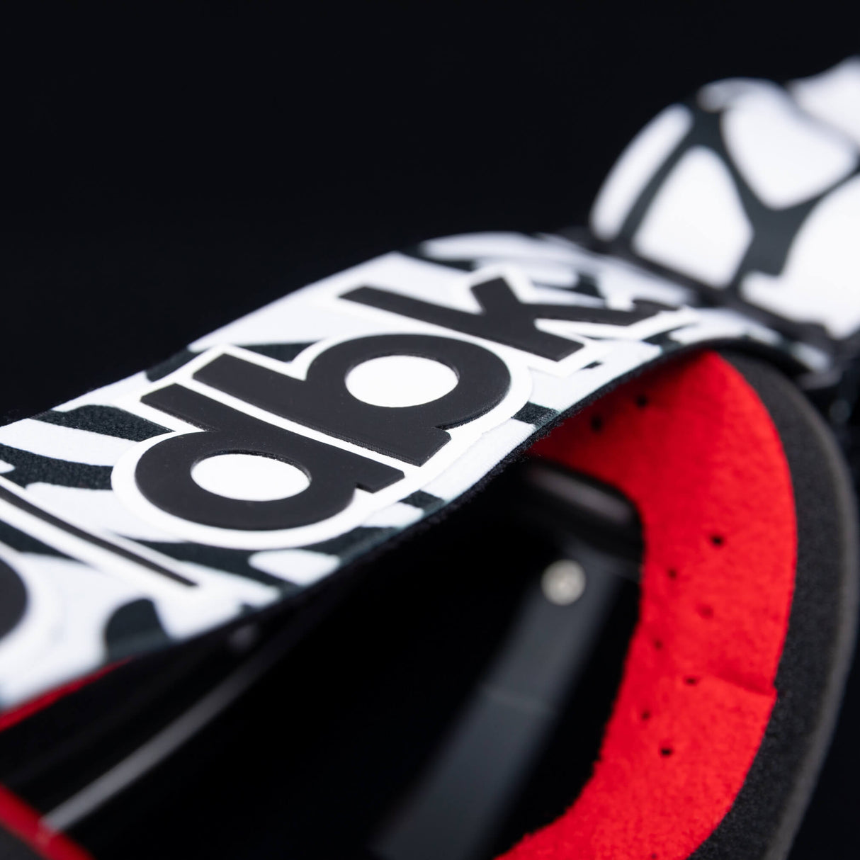 Helios goggle close-up with red inner foam and black-and-white graphic strap