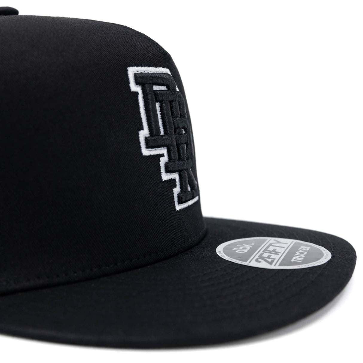 Black trucker cap side close-up with white DBK 2Fifty logo and round brim patch