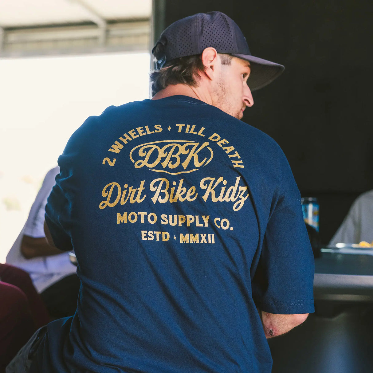 Blue logo T-shirt worn from behind, large gold back graphic and crew neck.