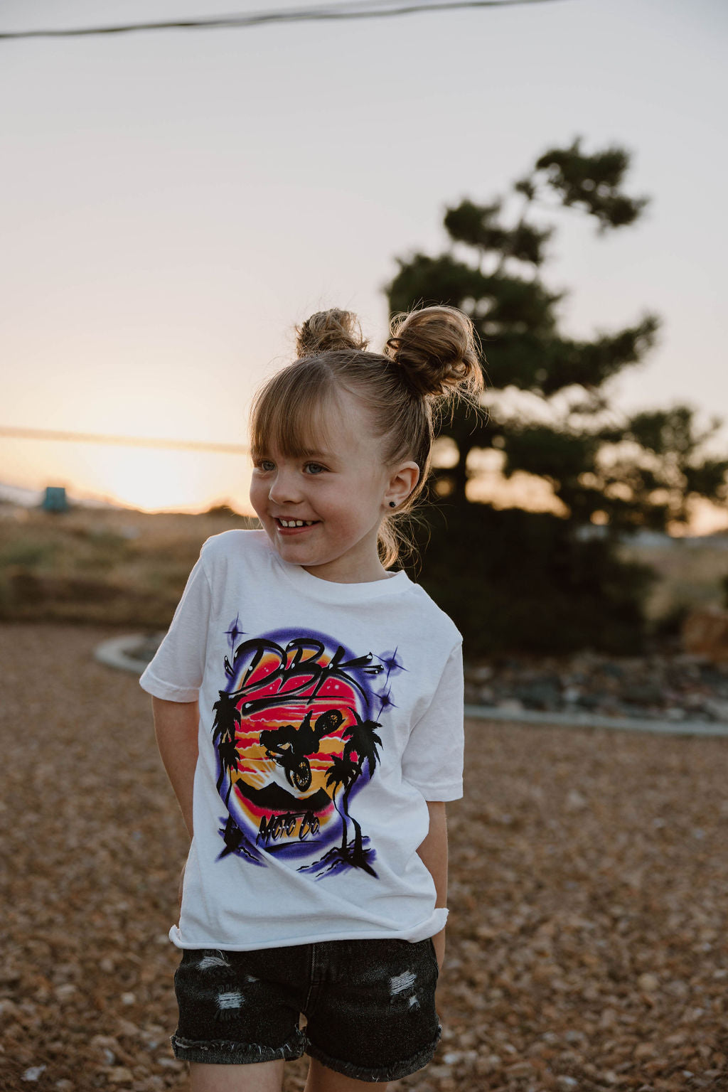 Youth girls white graphic T-shirt worn by a child, with colorful motorcycle front print