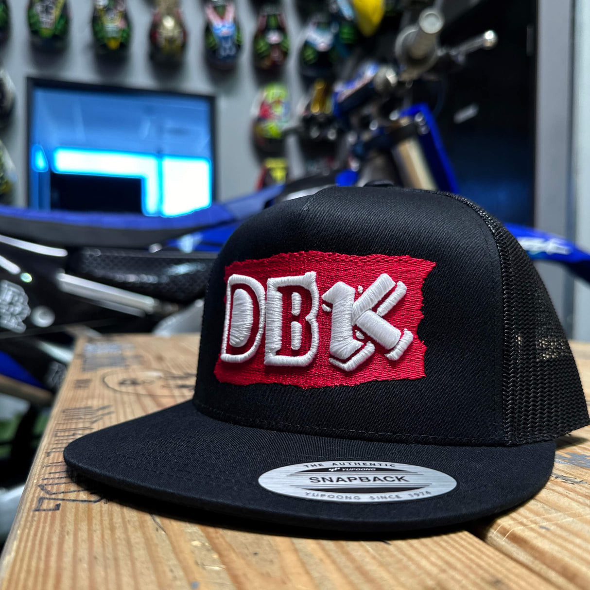 Black trucker hat with DB red logo patch and gray Snapback label on brim