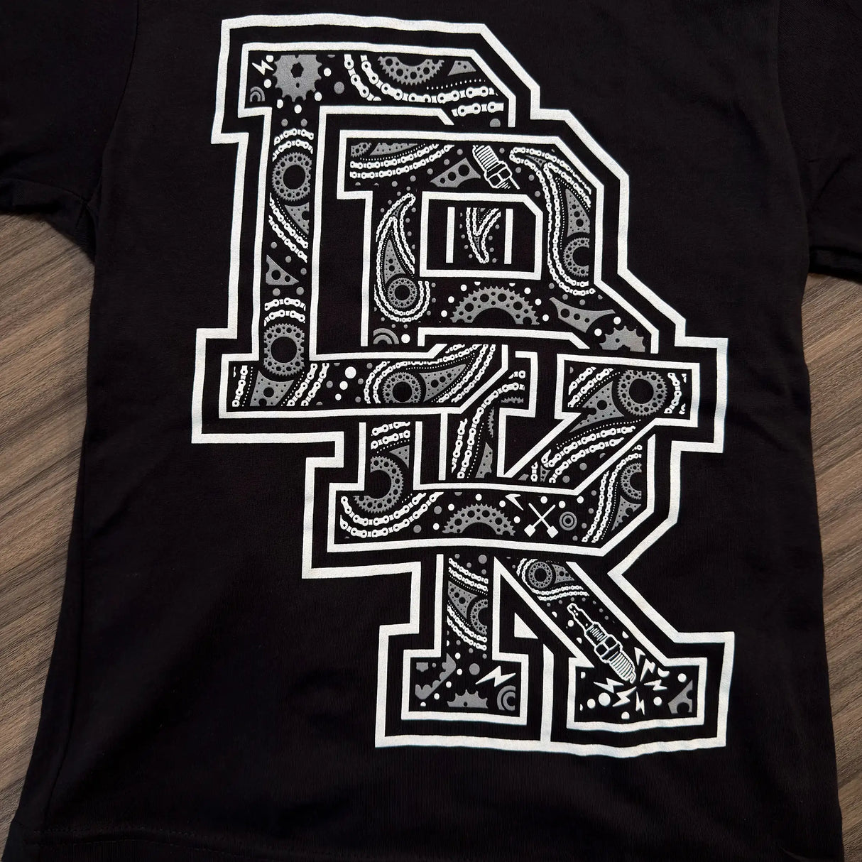 Black youth premium tee front view with big white patterned letter graphic, crew neck