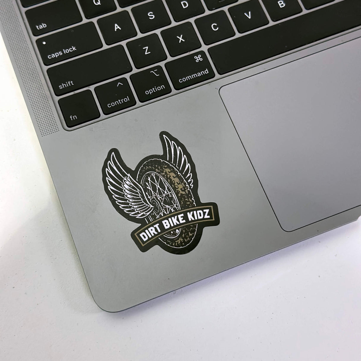 Single winged dirt bike logo sticker with DIRT BIKE KIDZ text on a laptop surface