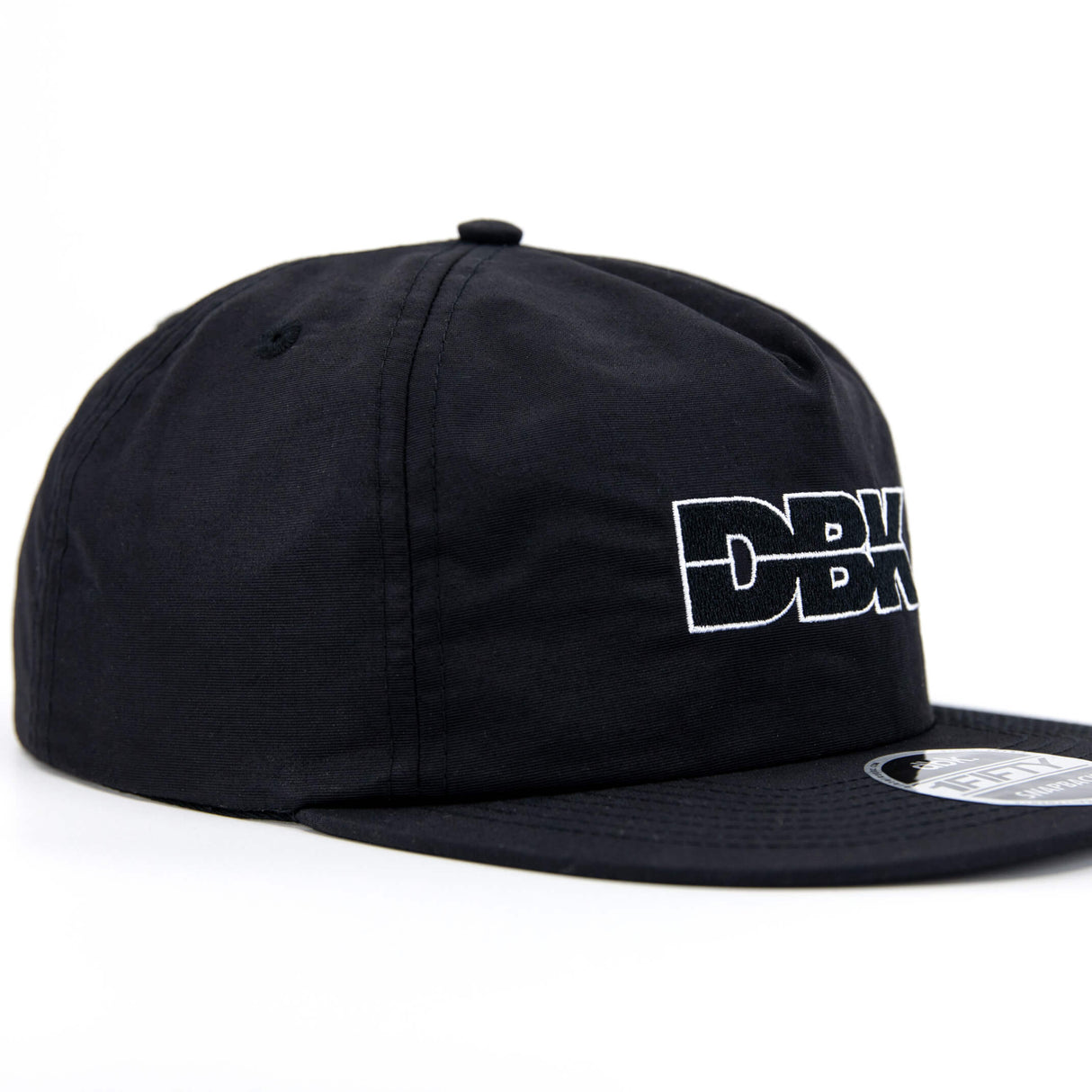 Black snapback cap angled side view with DBK logo and brim patch.
