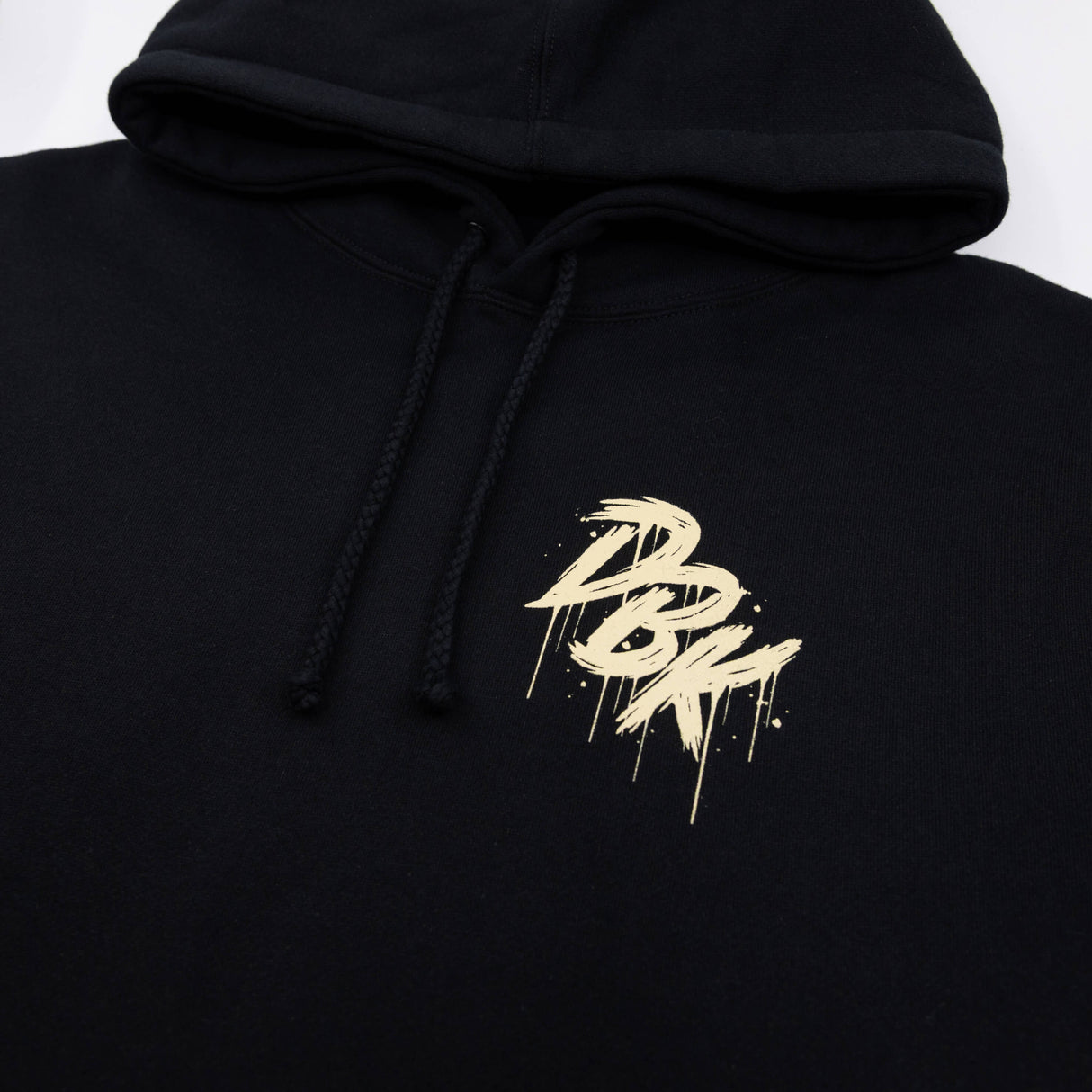 Black hoodie hood with drawstrings and small gold logo graphic