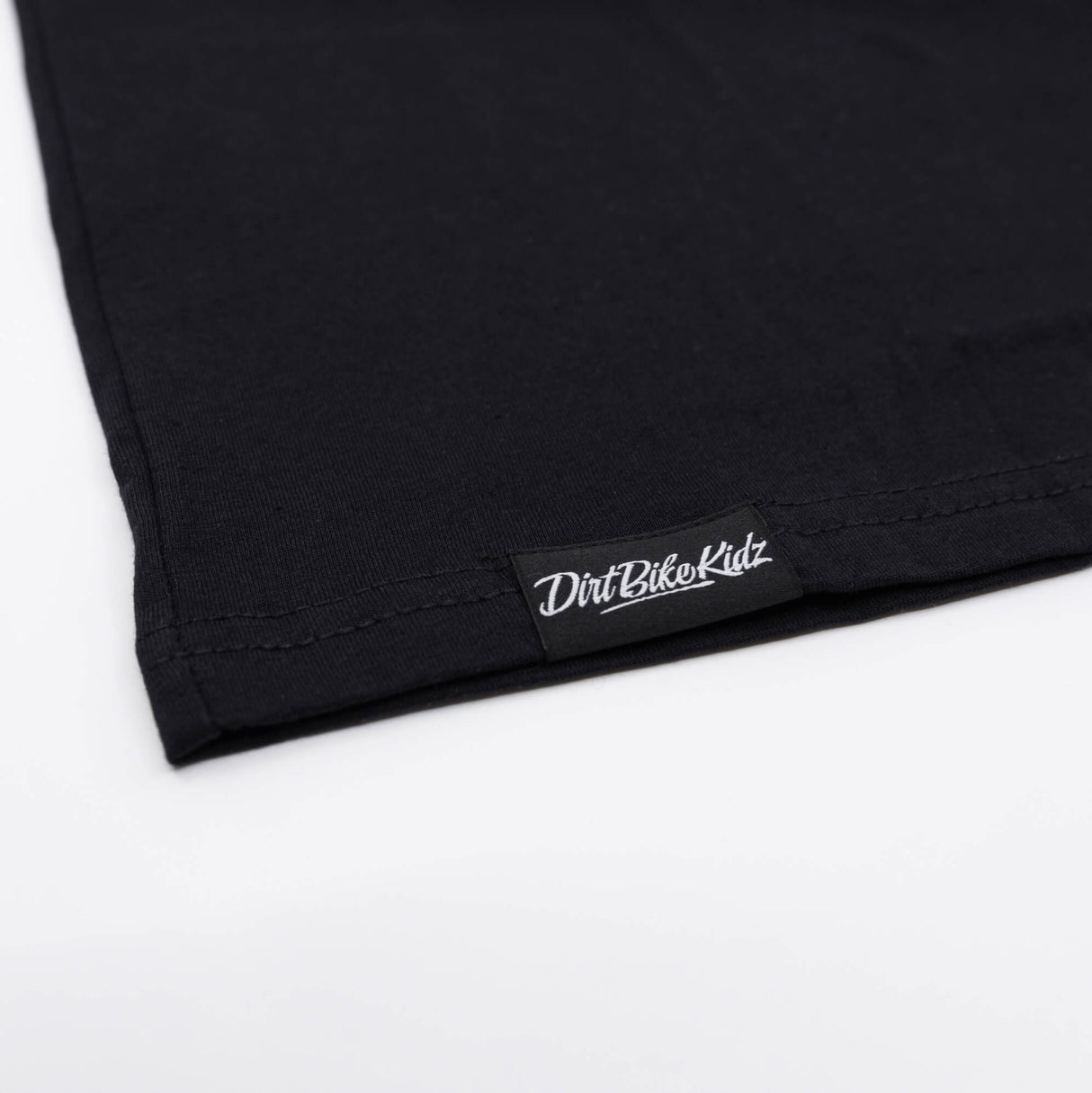 Youth black T-shirt hem with stitched brand label near bottom edge
