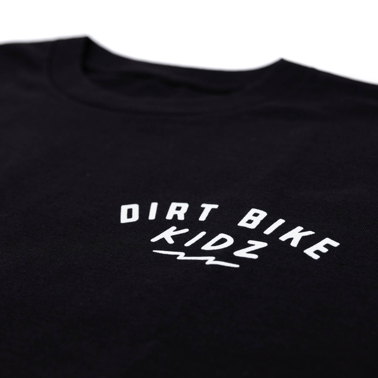 Close-up of black kids T-shirt front chest graphic reading “DIRT BIKE KIDZ”