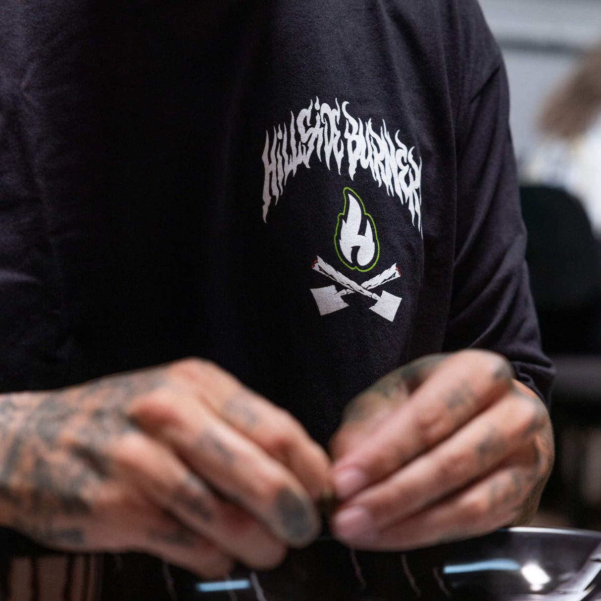 Black T-shirt close-up showing white flame icon and green flame lettering