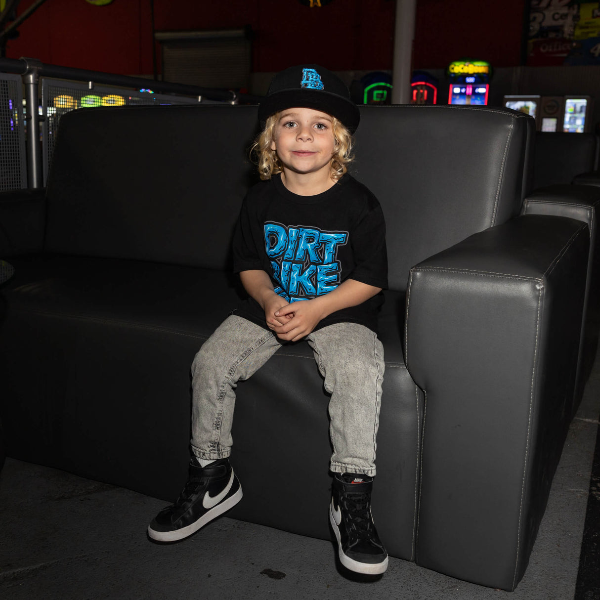 Youth tee worn by child: black shirt with blue “DIRT BIKE KIDZ” front graphic