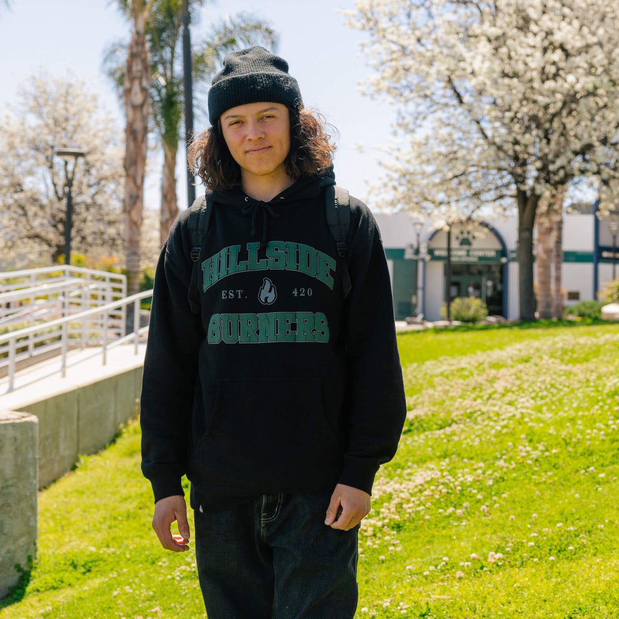 Varsity hoodie on model: black pullover with hood and green logo graphic