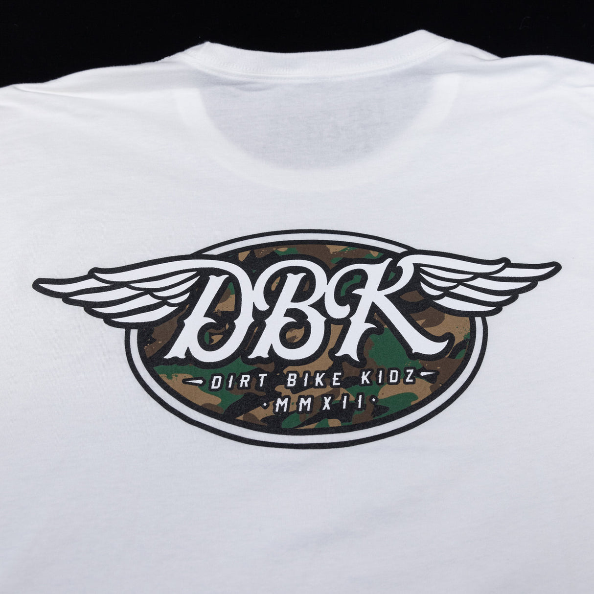 White tall tee with large winged DBK emblem featuring camo-style center graphic