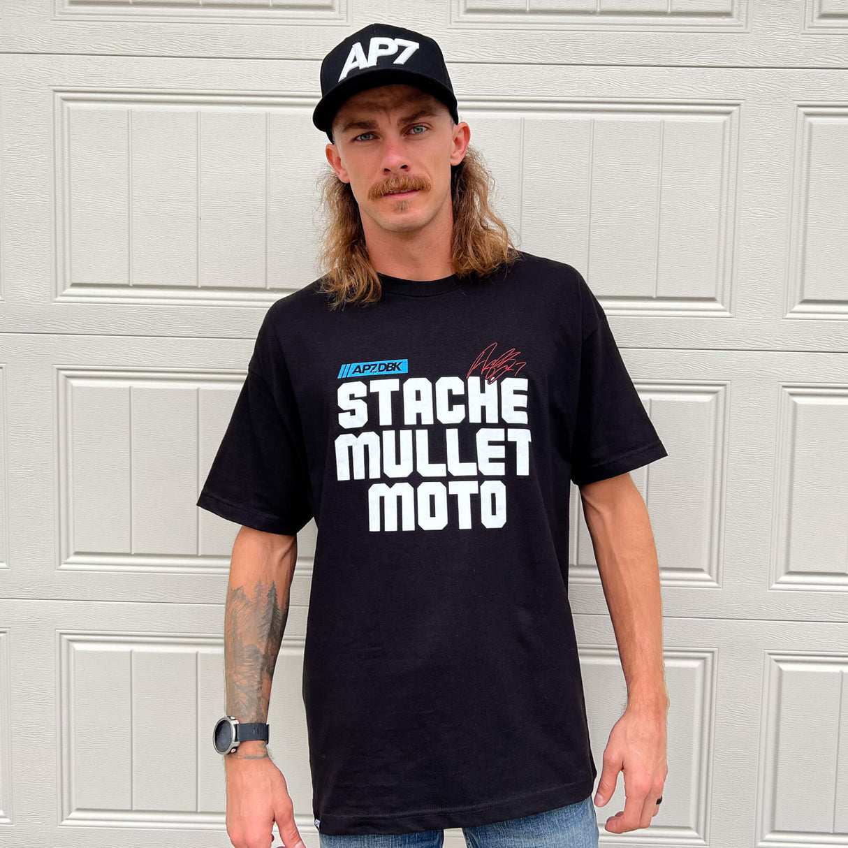 Black crewneck graphic tee worn by model, front “STACHE MULLET MOTO” print