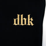 Black sweatpants leg with gold embroidered dbk logo centered on the fabric.