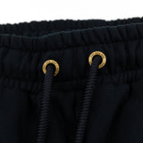 Black sweatpants drawstring eyelets with gold emblem rings at the waistband.