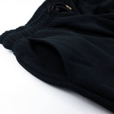 Black sweatpants close-up of ribbed waistband and tapered cuff hem.