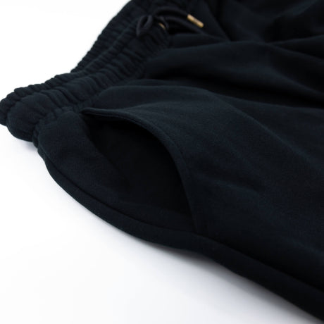 Black sweatpants close-up of ribbed waistband and tapered cuff hem.