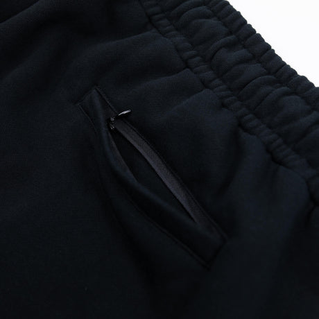 Black sweatpants pocket seam and smooth zipper accent detail near the thigh.