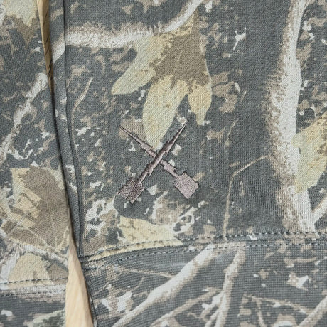 Youth camouflage hoodie sleeve seam with drawstring eyelets and drawcord.