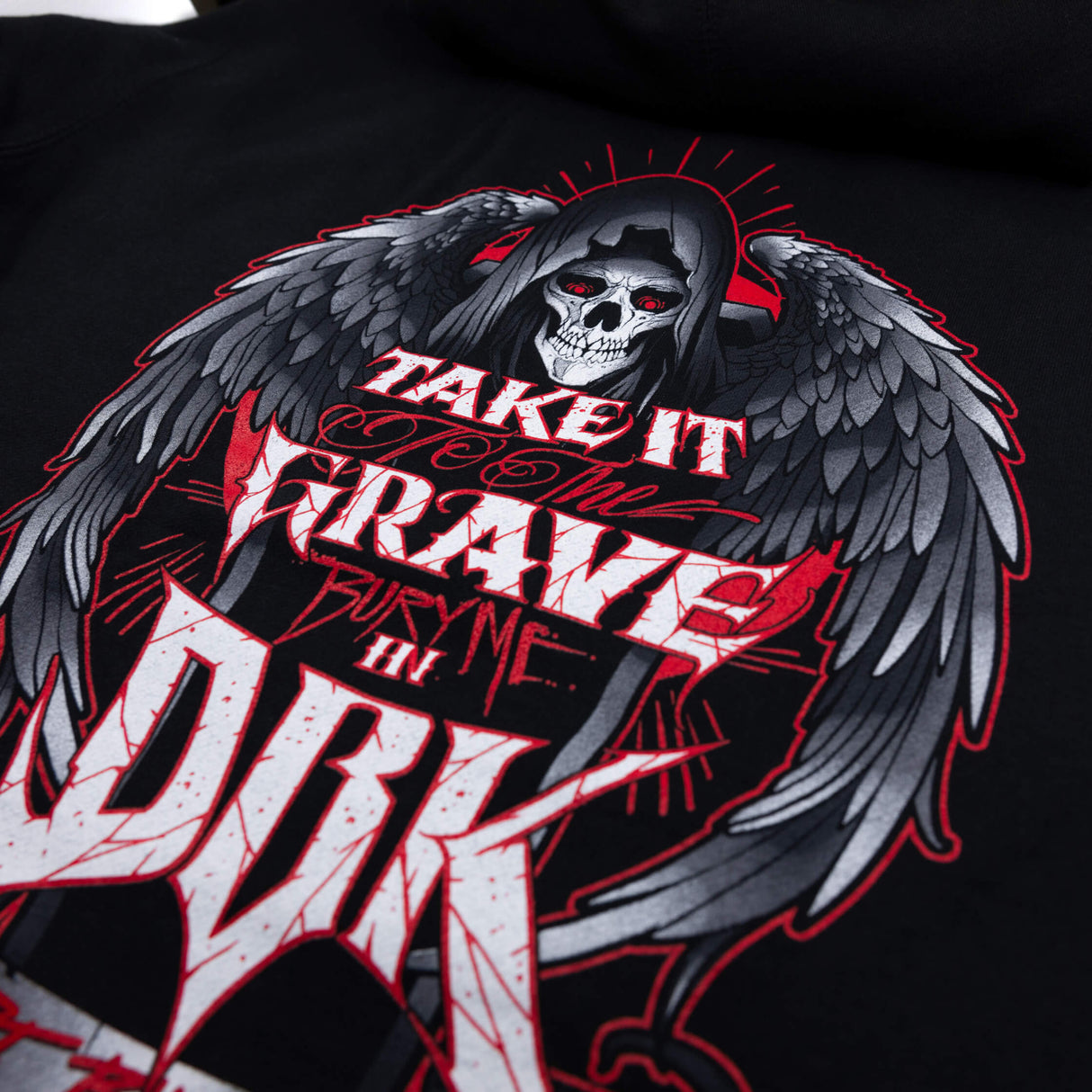 Black youth hoodie close-up of skull-wing design with red outlines and DRK lettering.