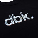 Black T-shirt close-up of metallic silver dbk logo print on chest.