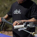 Black T-shirt with metallic silver dbk logo on chest, shown from mid-torso.