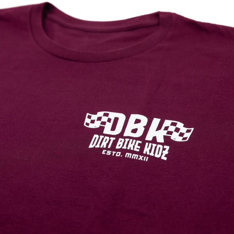 Maroon graphic T-shirt close-up of chest DBK logo and “ESTD. MMXII”
