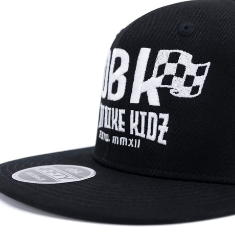 Black snapback cap close-up of white DBK logo on the crown