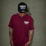 Burgundy graphic T-shirt worn by a model, featuring the DBK chest logo print