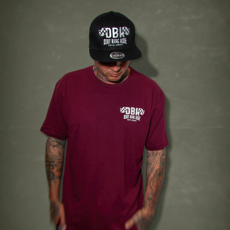 Burgundy graphic T-shirt worn by a model, featuring the DBK chest logo print