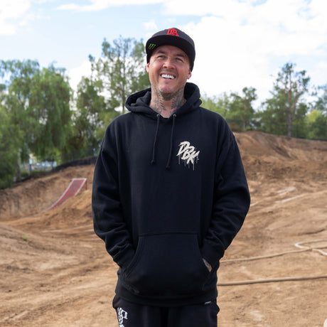 Black pullover hoodie with hood drawstrings and small gold logo on chest